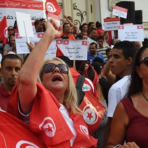 Des femmes brandissent le drapeau tunisien durant une manifestation lors de la Journée de la femme, 62 ans après le code personnel qui leur accordait des droits sans précédent dans un pays arabe.