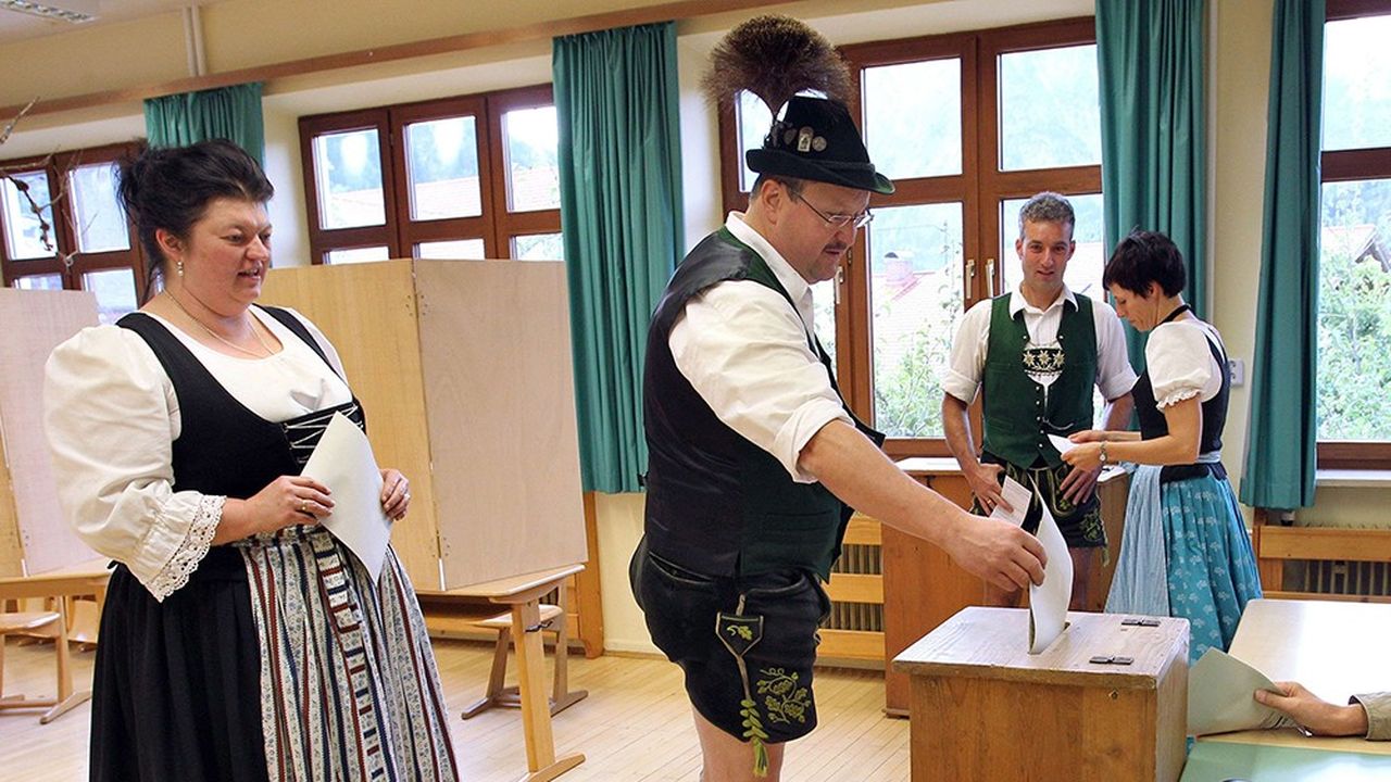 Des électeurs allemands, en tenue traditionnelle bavaroise, dans un bureau.