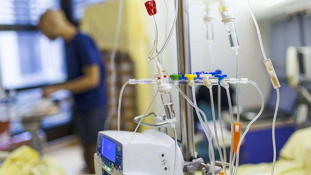 Un jeune patient atteint d'une leucémie se tient debout dans sa chambre, avec le matériel de perfusion nécessaire pour sa chimiothérapie.