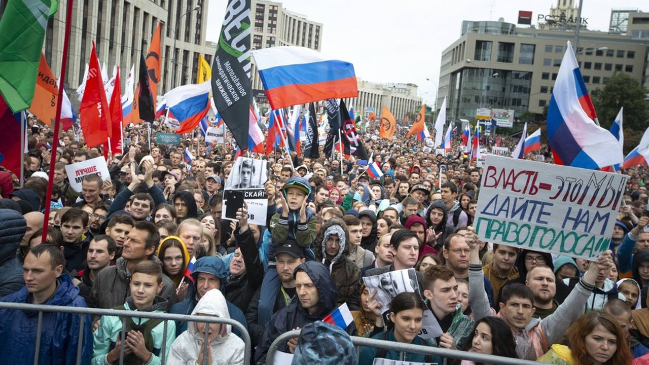Des manifestants brandissent le drapeau national et celui de divers partis politiques lors de la manifestation de samedi dernier, à Moscou.
