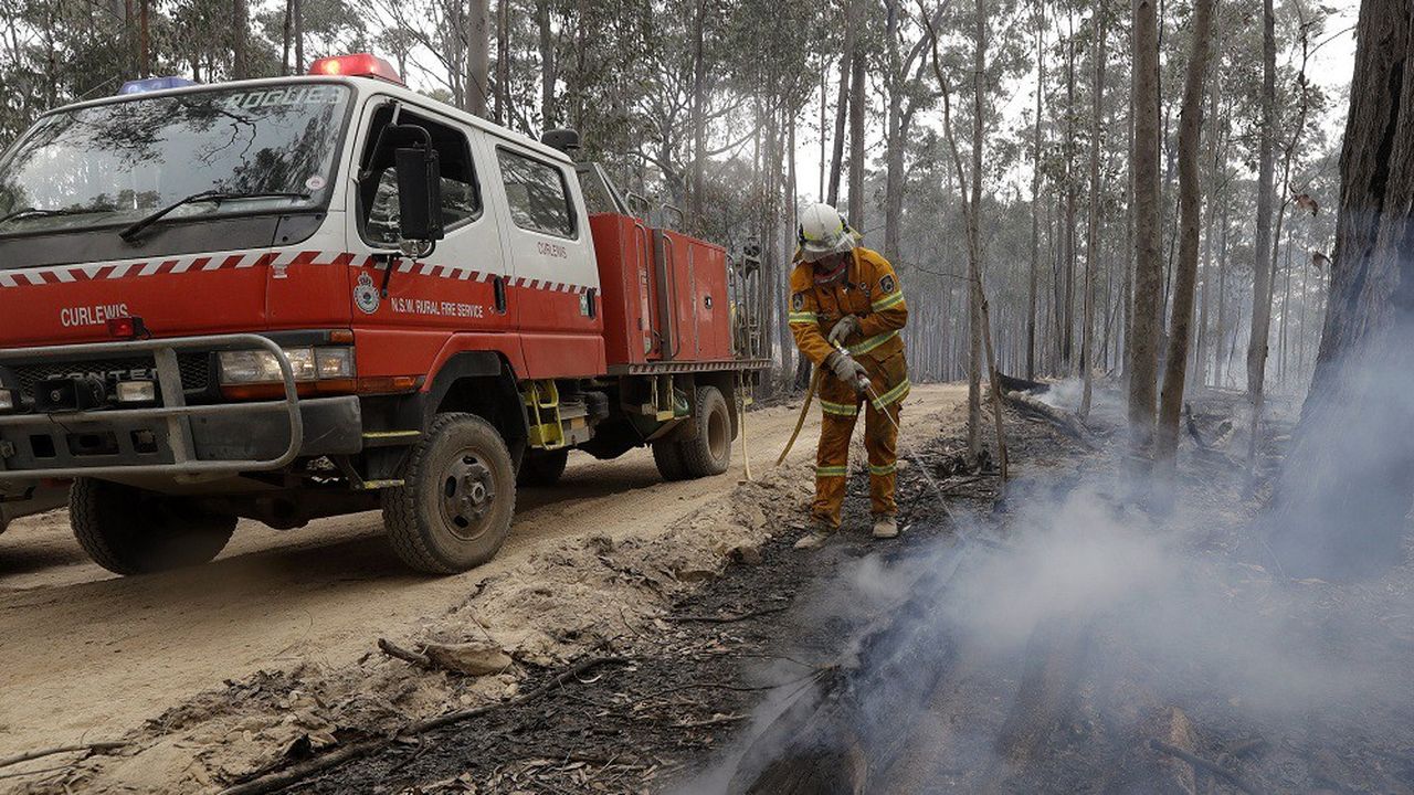 Une équipe de pompiers patrouille auprès d'un feu sous contrôle à Bodalla, en Australie, le 12 janvier.