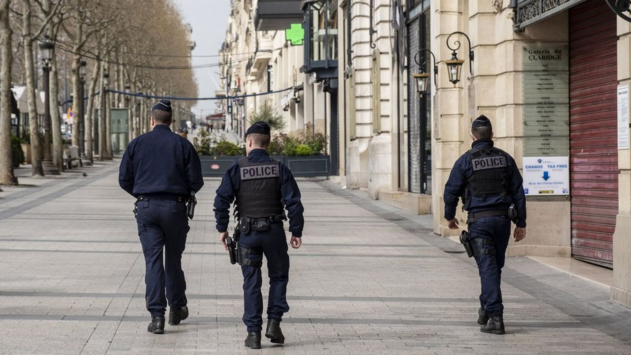 Un groupe de policier marche à Paris sur l'avenue des Champs-Elysées vide le premier jour du confinement de la population française pour lutter contre l'épidémie de coronavirus.