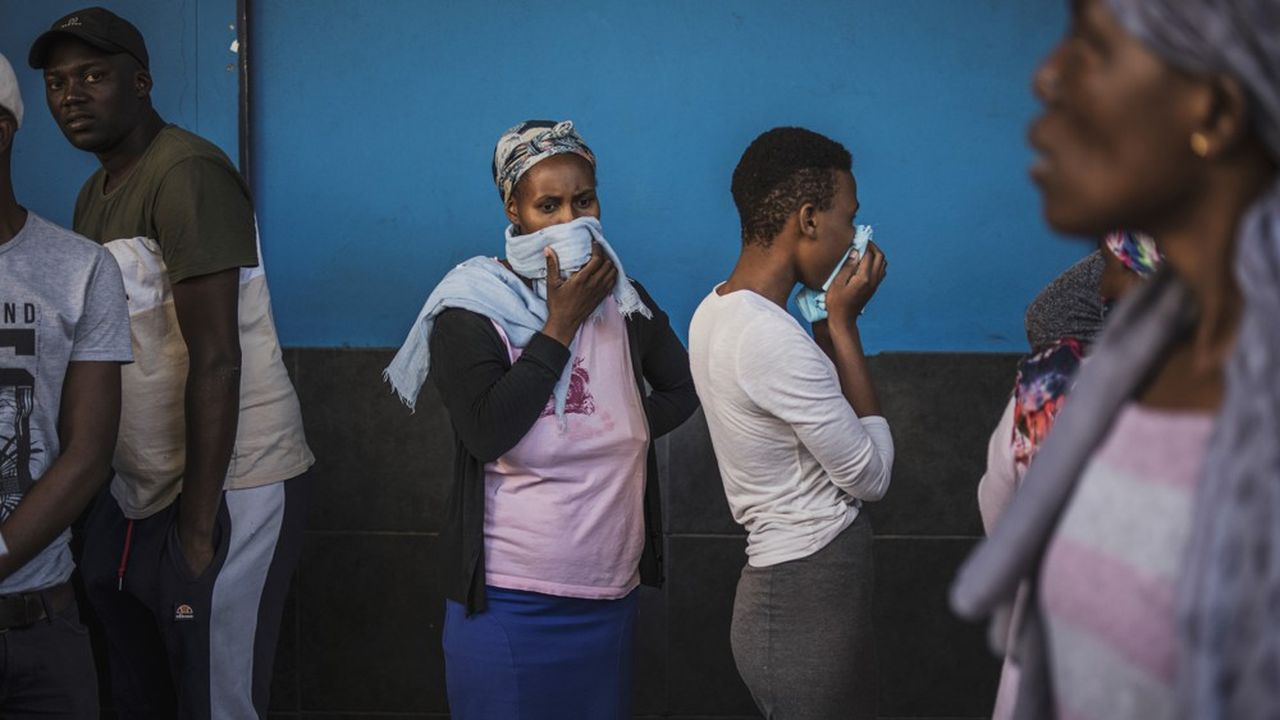 Des Sud-Africains, devant un supermarché Johannesbourg le 27 mars dernier, couvrent leur visage pour se protéger du coronavirus.