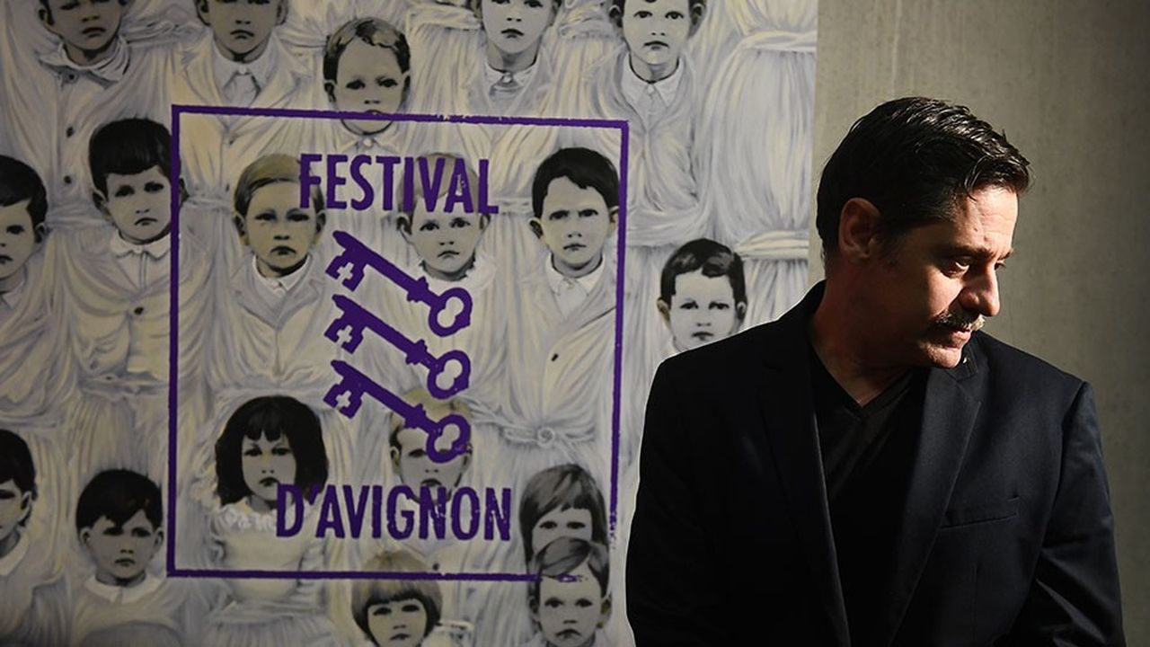 Le directeur du Festival d'Avignon posant devant l'affiche de la 72e édition.