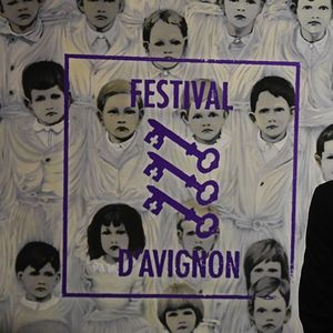 Le directeur du Festival d'Avignon posant devant l'affiche de la 72e édition.