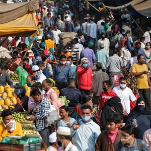 Un agent de santé teste la température des commerçants sur un marché d'Ahmedabad, alors que se profile en Inde une gigantesque campagne de vaccination.