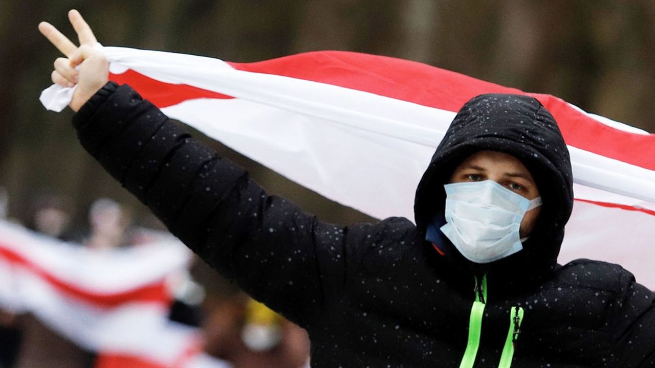 Un manifestant brandit le drapeau de l'opposition, inspiré de celui du Bélarus lors des défilés contre la réélection jugée frauduleuse du président Alexandre Loukachenko, à Minsk
