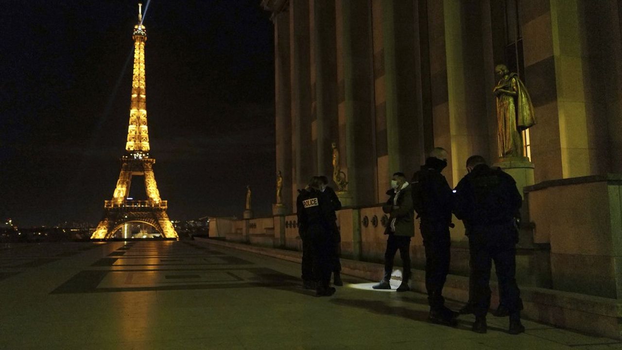 Des policiers contrôlent des passants devant la Tour Eiffel, à Paris, le 15 décembre, alors que le pays est soumis à un couvre-feu de 20 heures à 6 heures du matin.