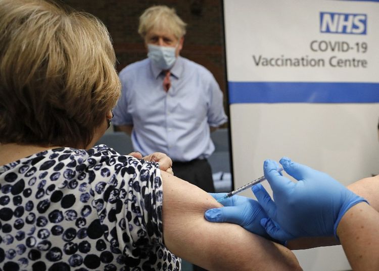 Boris Johnson regarde l'infirmière Rebecca Cathersides recevoir sa première injection de vaccin au Guy's Hospital de Londres le 8 décembre 2020.