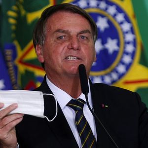 Le président brésilien tient à la main son masque lors d'une cérémonie au palais Planalto à Brasilia, le 10 juin 2021.