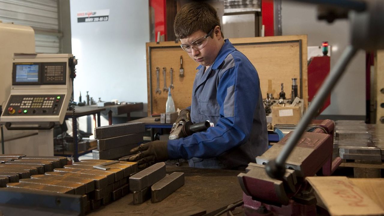 Un jeune apprenti mécanicien en train d'usiner des pièces métalliques.