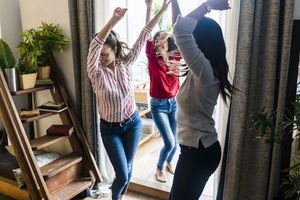 Three women at home having a party and dancing