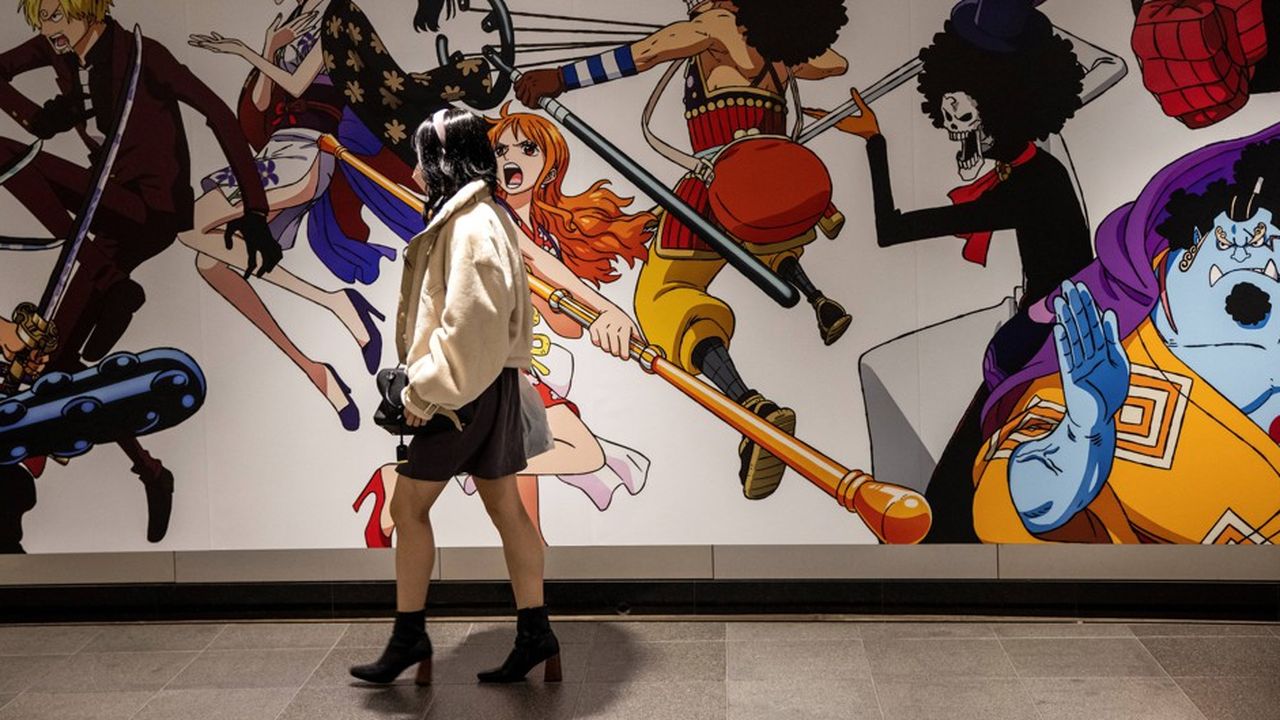 Sur cette photo prise le 18 novembre 2021, une femme passe devant une affiche de personnages de l'animé 'One Piece' à Tokyo, avant la sortie du 1.000e épisode.