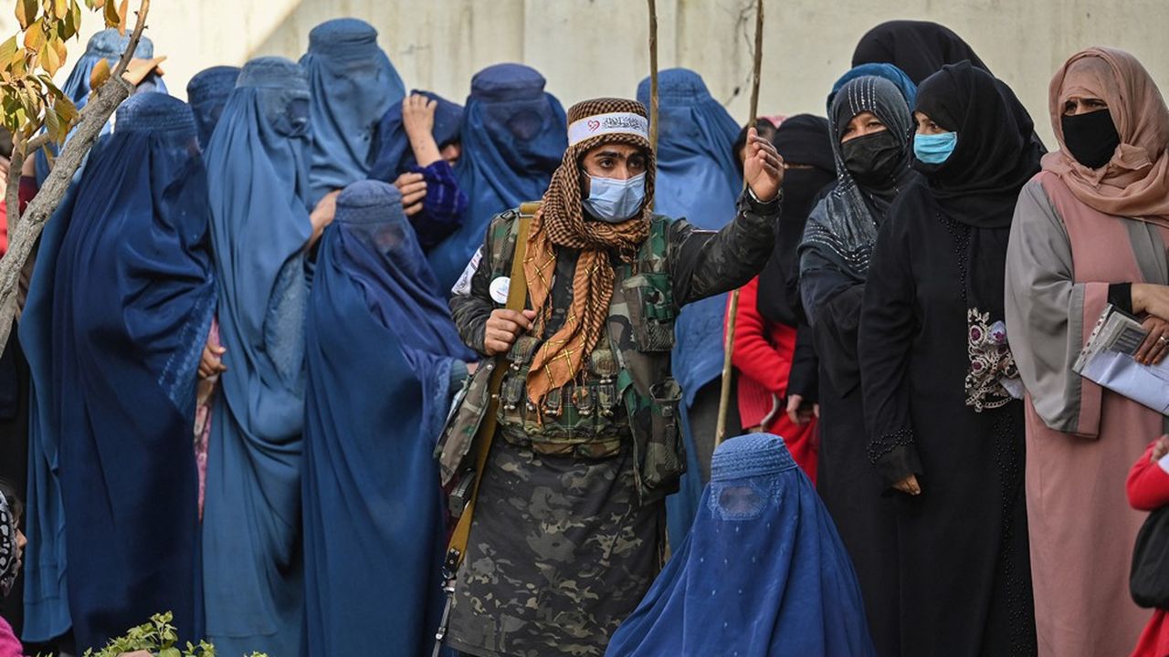 Un garde taliban surveille des femmes afghanes faisant la queue lors d'une distribution d'aide du Programme alimentaire mondial à Kaboul.