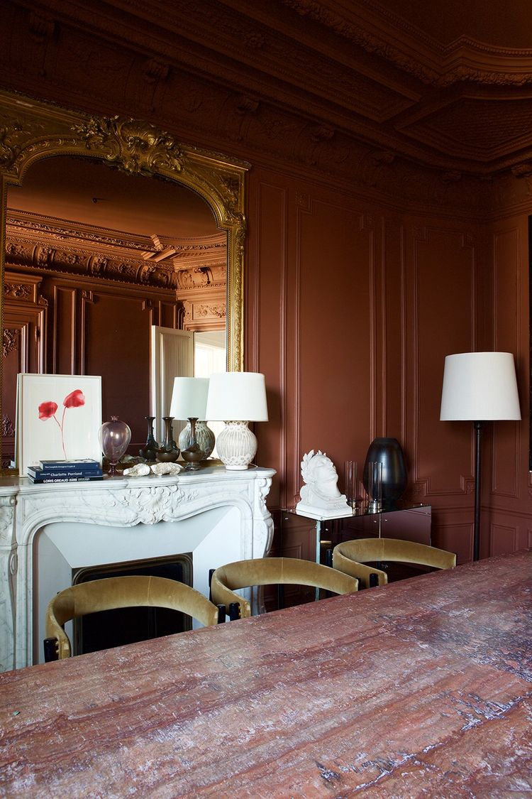 Dans la salle à manger aux boiseries chocolat, table en marbre dessinée par Luis Laplace, chaises italiennes des années 60 et aquarelle de Louise Bourgeois.