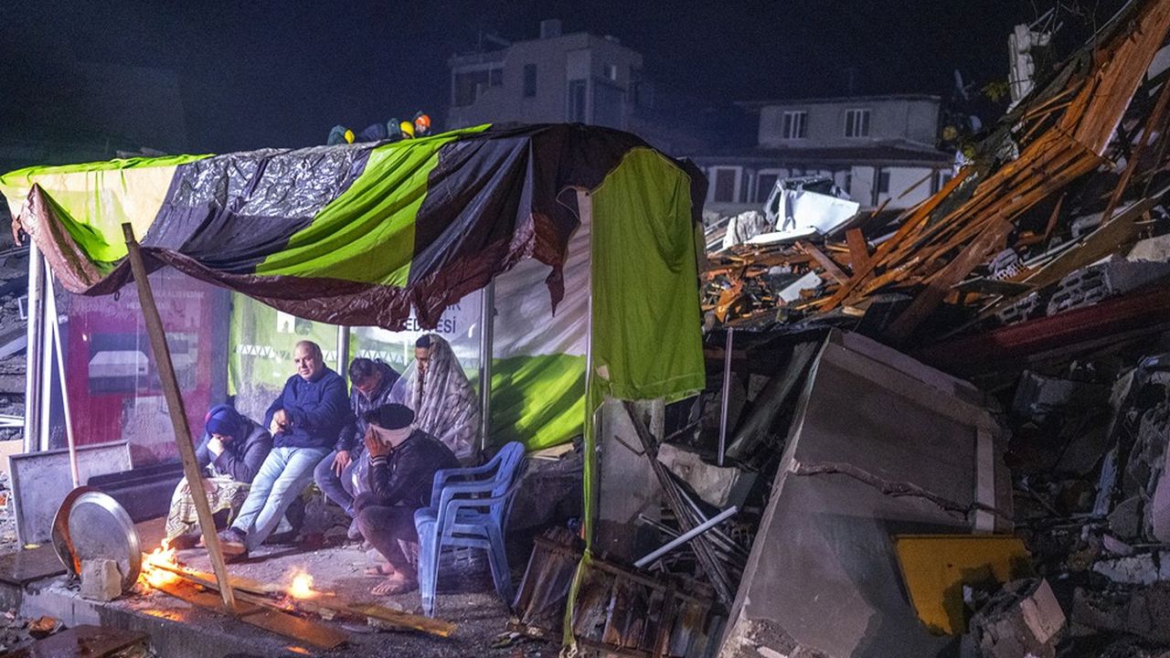 Des rescapés se réchauffent près d'un feu dans la ville de Hatay, ravagée par le séisme.