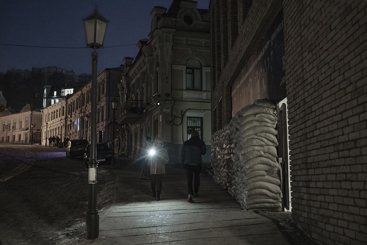 Dans Kiev privée de lumière, le 8 février 2023, une femme marche en s'éclairant d'une lampe torche. 
