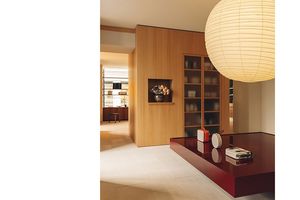 Le bardage en bois sur le mur bibliothèque et le meuble présentoir rouge bordeaux confèrent à l'espace, teinté de beige, de la douceur.