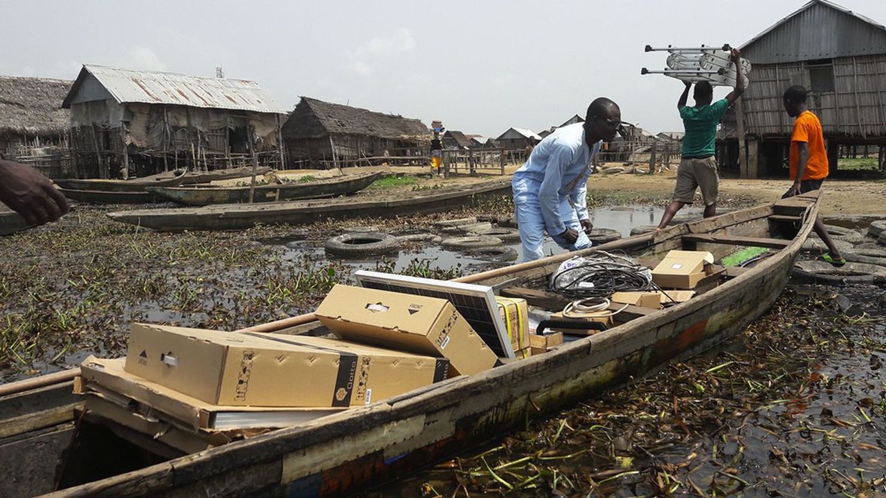 Des employés de Qotto installent des kits solaires dans un village lacustre près de Cotonou, au Bénin.