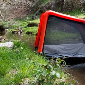 Le modèle Cabaniste conçu et commercialisé par 2R Aventure est une tente gonflable tout-terrain (ici posée sur une rivière) d'une quinzaine de kilos, transportable comme une coquille d'escargot sur le dos.