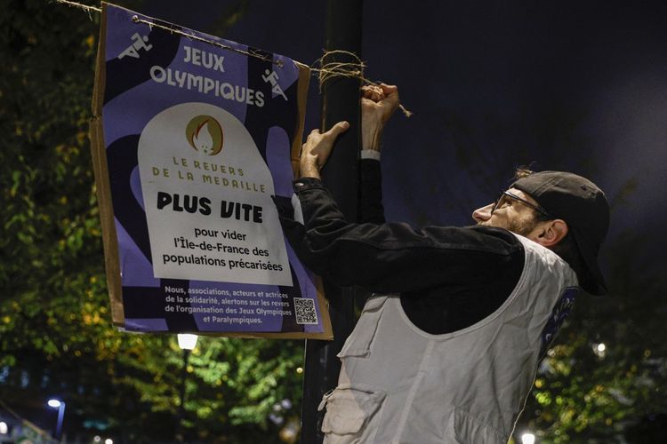 Un activiste colle une pancarte au siège du Comité olympique dans la nuit de dimanche à ce lundi.