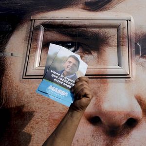 Un supporter de Sergio Massa brandit une affichette devant l'énorme affiche du candidat Javier Milei.