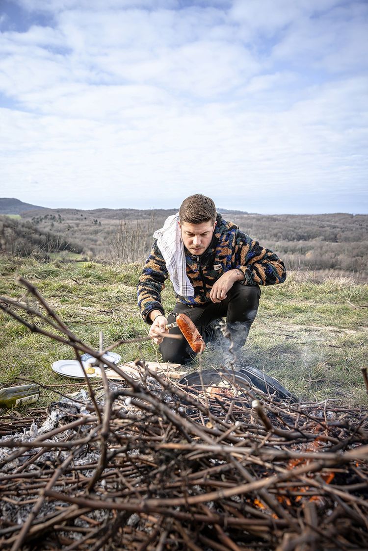 Mathias Marc en train de cuisiner une saucisse vigneronne, photo extraite de son livre « In Situ, recettes signatures d'un cuisinier du massif jurassien » aux éditions du Chêne.