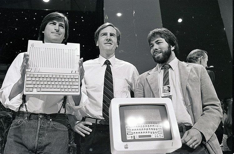 En 1984, Steve Jobs et Steve Wozniak, cofondateurs d'Apple, entourant John Sculley, le patron de l'époque, présentent l'ordinateur Apple IIc. 