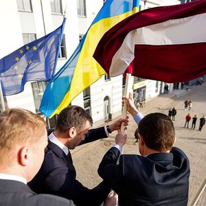 Le maire adjoint de Riga Edvards Smiltens, le maire Martins Stakis et l'ambassadeur d'Ukraine en Lettonie Alexandr Mischenko portant le drapeau ukrainien sur le Parlement letton.