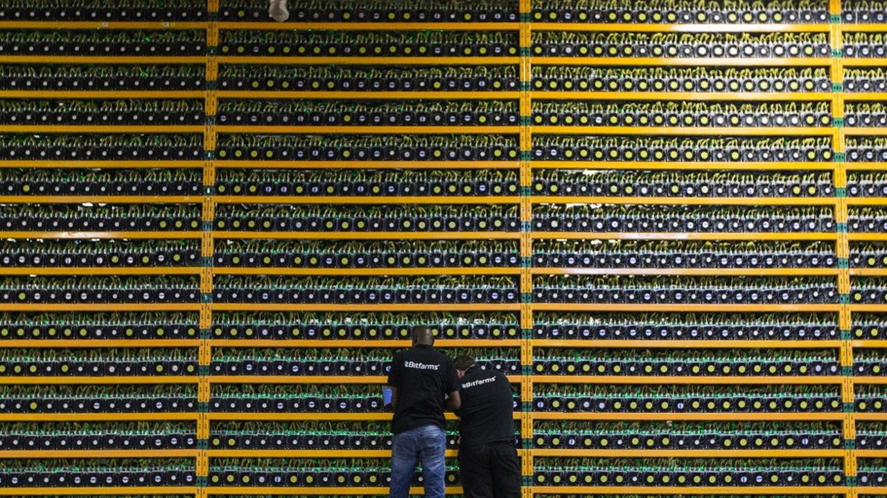 Deux techniciens inspectent le mineur de bitcoins de Bitfarms à Saint-Hyacinthe, au Québec, le 19 mars 2018.