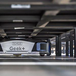 Les robots de Geek + se glissent sous des étagères pour les amener au poste des préparateurs de commandes.