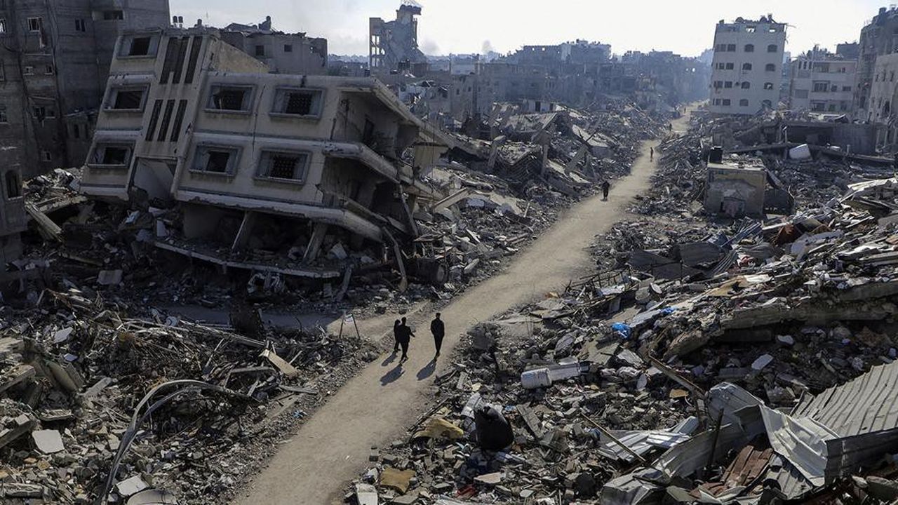 Des civils longent une rue parsemée d'immeubles détruits dans le camp de Jabalia, dans le nord de la bande de Gaza.