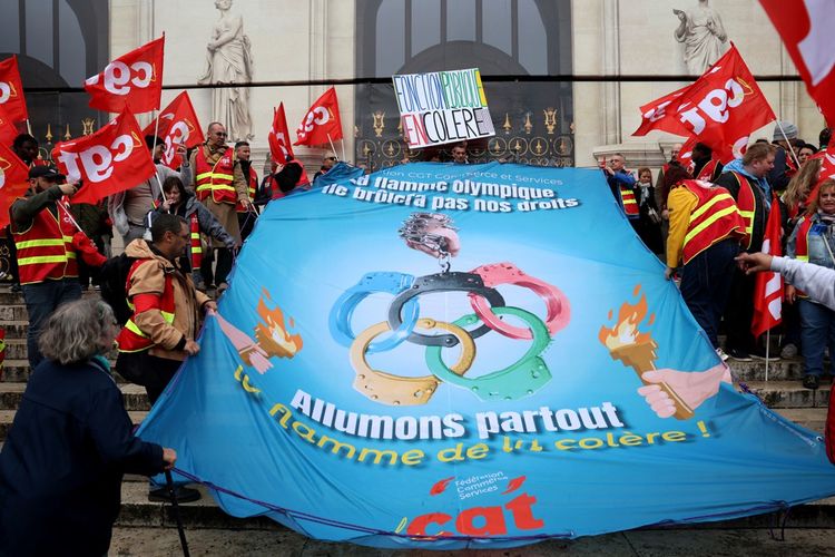 Brandissant des flambeaux symbolisant la flamme olympique, les manifestants ont défilé derrière une banderole promettant « l'incendie social » si « la flamme des JO brûle le code du travail ».