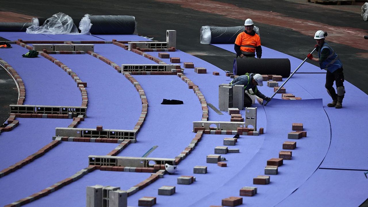 Des ouvriers installent la nouvelle piste d'athlétisme violette au Stade de France le 09 avril 2024.