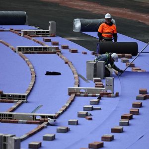 Des ouvriers installent la nouvelle piste d'athlétisme violette au Stade de France le 09 avril 2024.